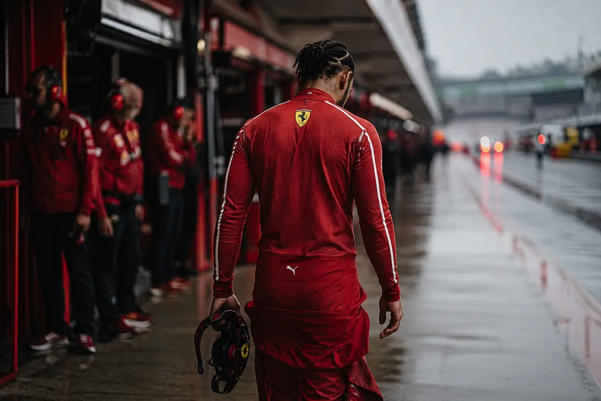 Hamilton, pilota della Ferrari, a testa bassa e col volante in mano nel box