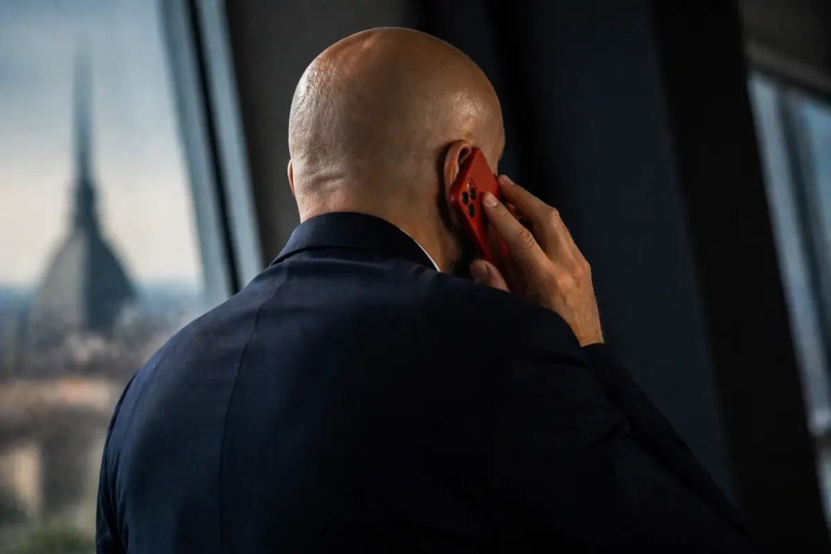 Un uomo che somiglia a Spalletti di spalle mentre palla al telefono, immagine creata con intelligenza artificiale